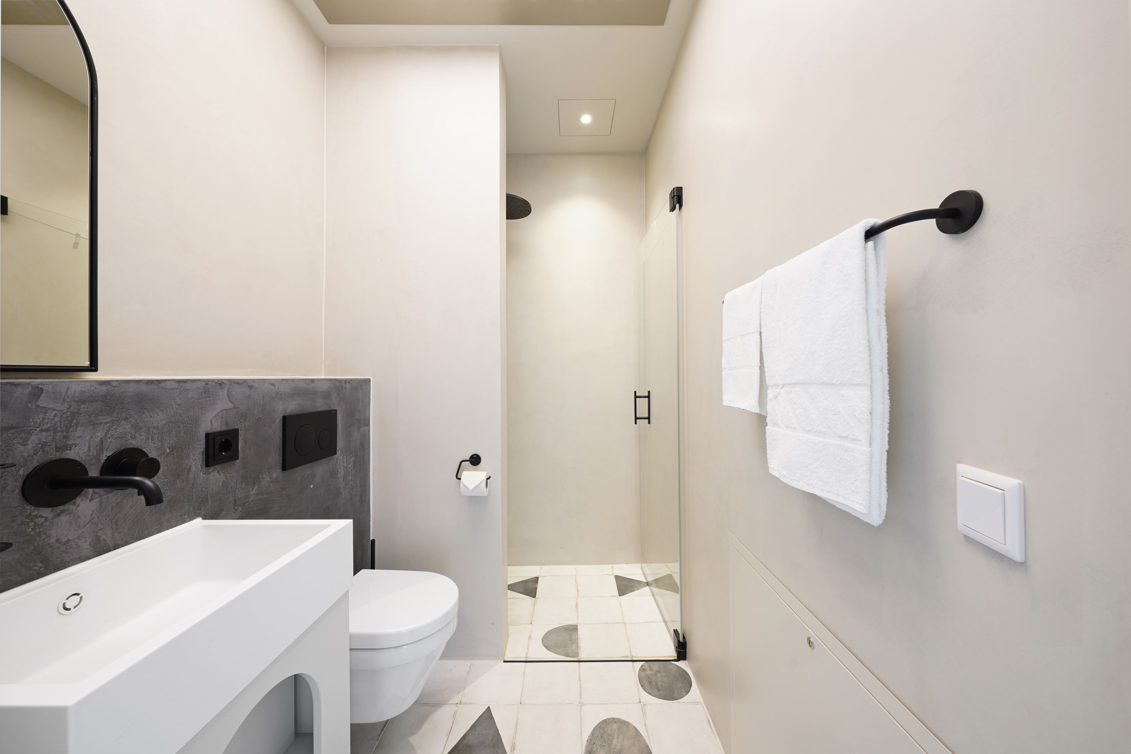Een moderne badkamer met een groot wit wastafel, een toilet en een douchehoek.