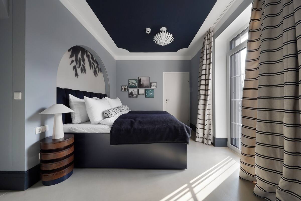 Une chambre à coucher moderne avec un lit, une table de chevet et un luminaire au plafond.