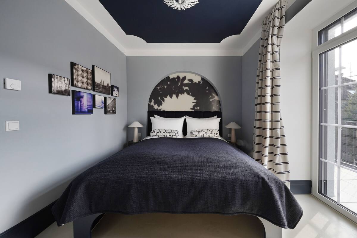 Une chambre à coucher avec un lit, une grande fenêtre et un luminaire au plafond.