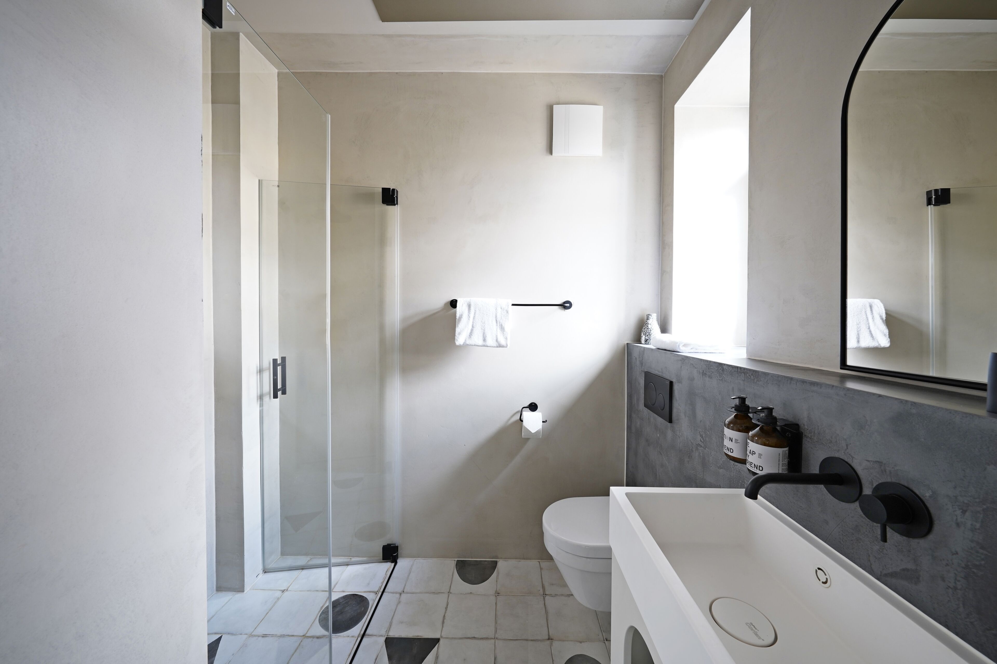 A modern bathroom with a glass shower enclosure, a white sink, and a large mirror.