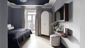 Une chambre à coucher avec un lit, des rideaux, une coiffeuse avec un miroir et un petit tabouret.