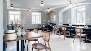 Un espace repas moderne avec des tables et des chaises en bois, de grandes fenêtres et des vases décoratifs.