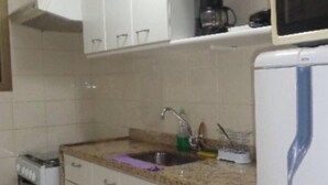 A kitchen with white cabinets, a granite countertop, a sink, a coffee maker, and a microwave. - Ipanema Beach (Rio de Janeiro)