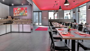 A modern restaurant with a red ceiling, black chairs, and a large painting on the wall. - Ocak Hotel (Berlin)