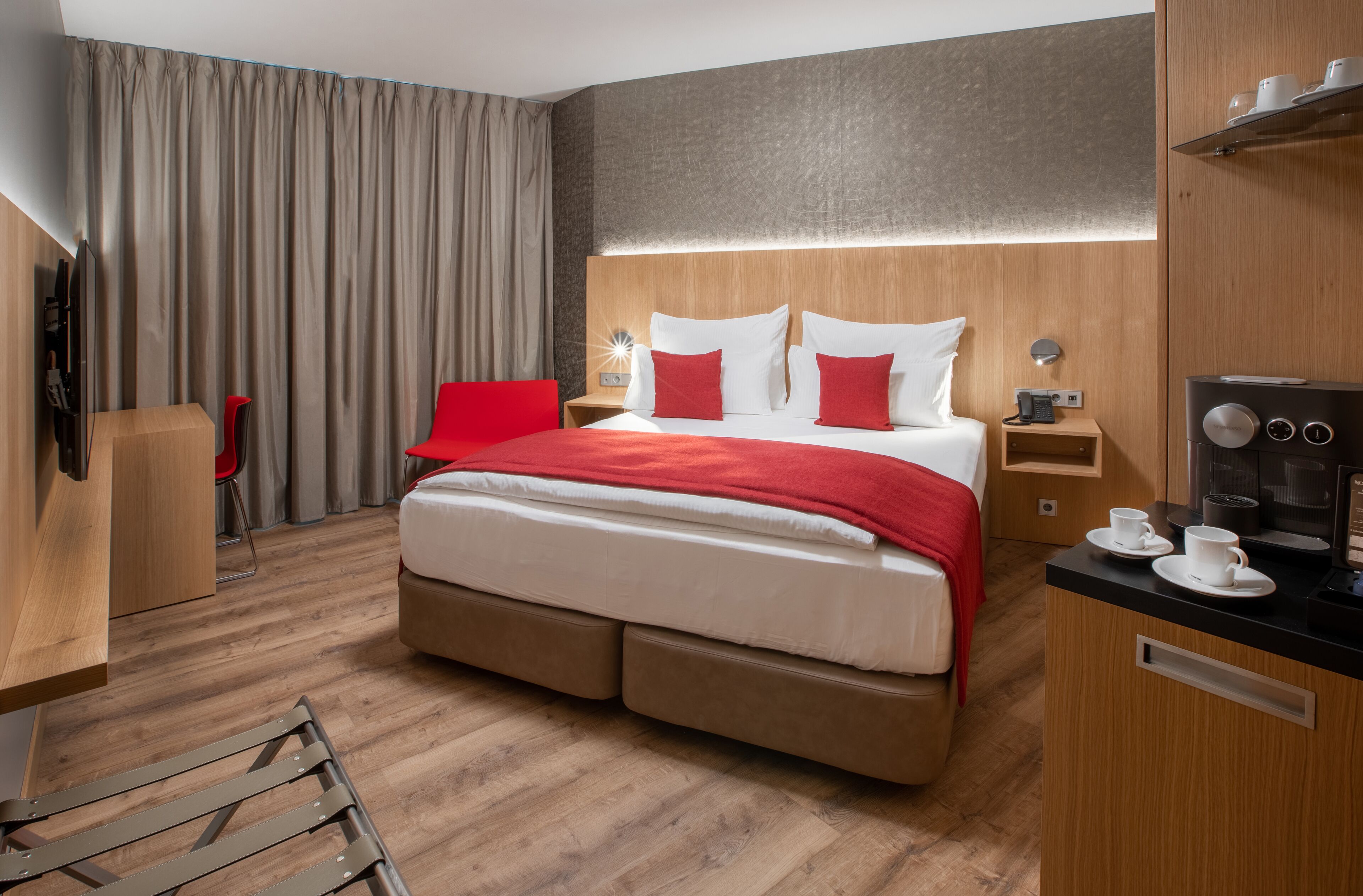 Une chambre d’hôtel moderne équipée d’un grand lit, d’un bureau, d’une chaise, d’une télévision et d’une machine à café.
