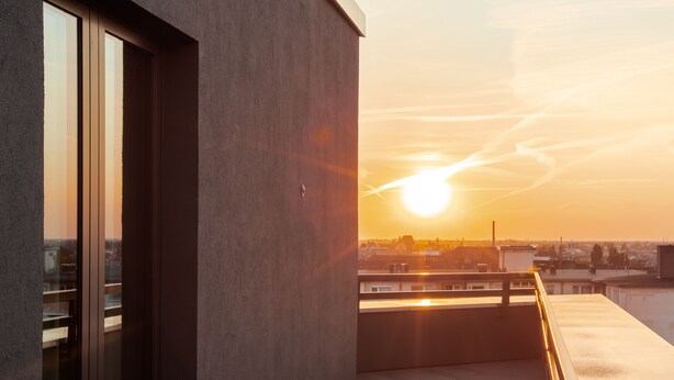 A modern building with a balcony overlooking a cityscape during sunset. - Ocak Hotel (Berlin)