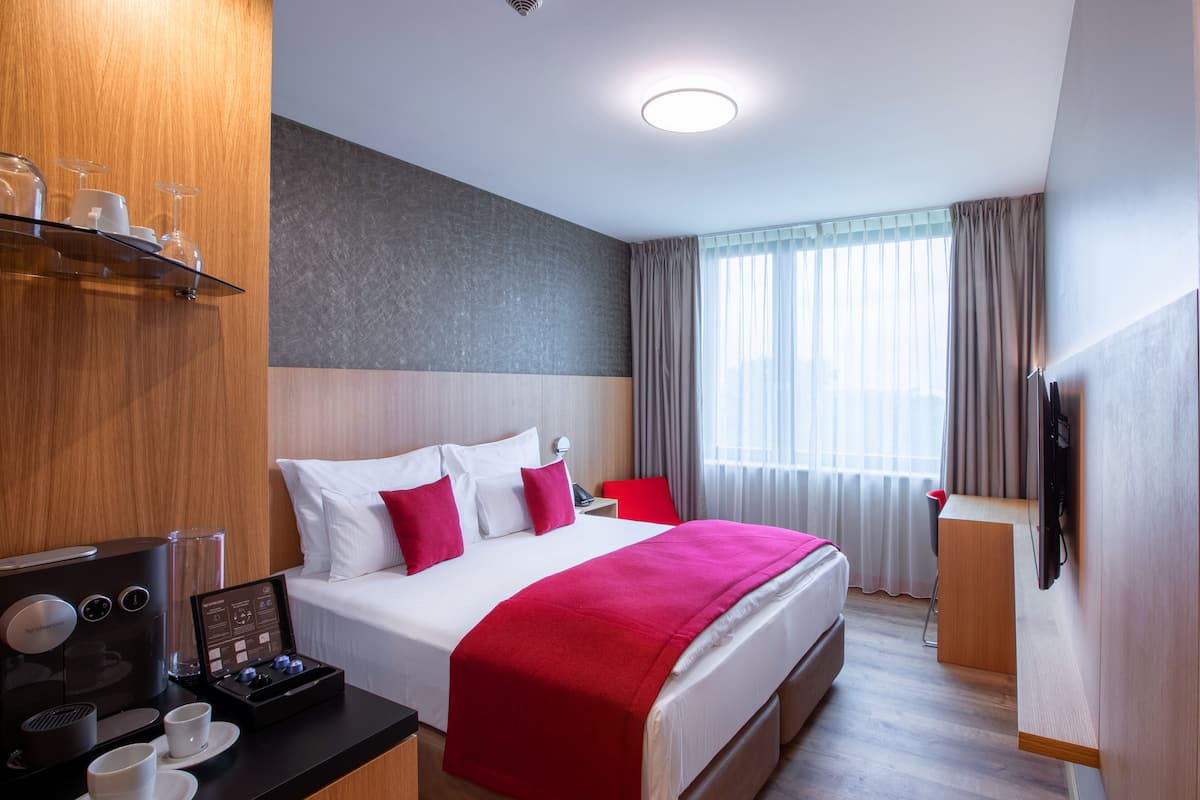 A hotel room with a bed, a coffee machine, and a TV.