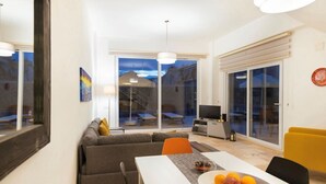 Una sala de estar moderna con un sofá, una mesa de comedor y un televisor.
