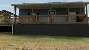 A single-story building with a covered porch and a fenced deck.