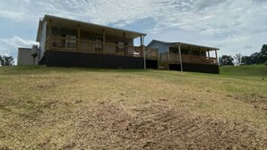 A two-story building with a covered porch and a fenced yard.