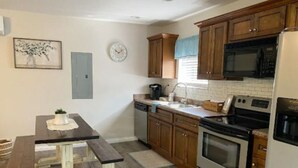 A kitchen with wooden cabinets, a microwave, an oven, a sink, and a dining table with a placemat.