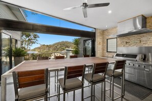 Una cocina moderna con una isla grande, electrodomésticos de acero inoxidable y vistas del paisaje circundante.