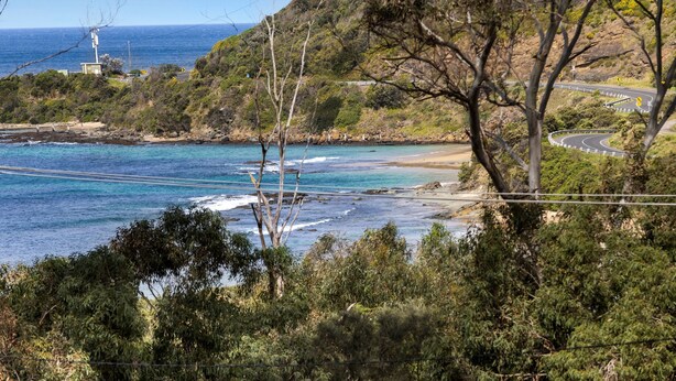 Camí costaner amb vista a l'oceà i un far a la distància.