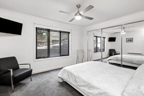 A hotel room with a bed, a chair, a TV, a ceiling fan, and a large window. - Wye Times (Wye River)