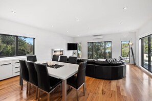 A modern interior with a dining area, a fireplace, and large windows. - Wye Times (Wye River)