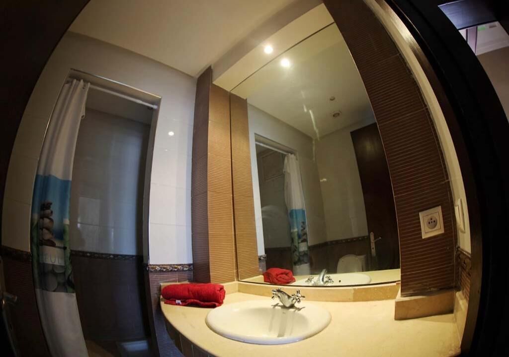 A bathroom with a large mirror, a sink, and a shower area.
