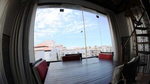 A dining area with a curved table and red cushions, a view of buildings through a window, and a staircase with ornate railings. - Residence Marina Agadir 4821 (Agadir)