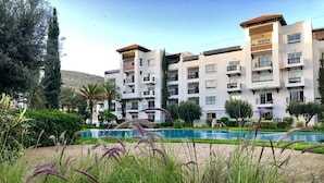 A multi-story hotel with balconies, a swimming pool, and lush greenery. - Residence Marina Agadir 4821 (Agadir)