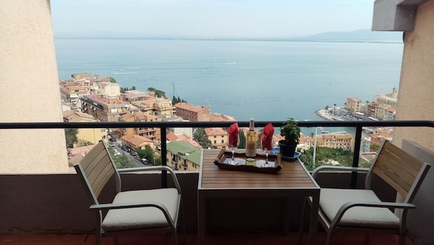 A balcony with a table set for two, overlooking a coastal cityscape.