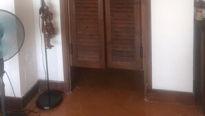 A room with a wooden door, a standing fan, and a floor lamp.