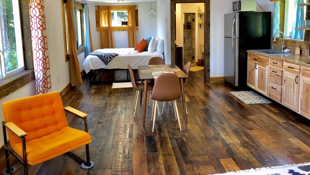 Una habitación amplia con cama en altillo, comedor y cocina.