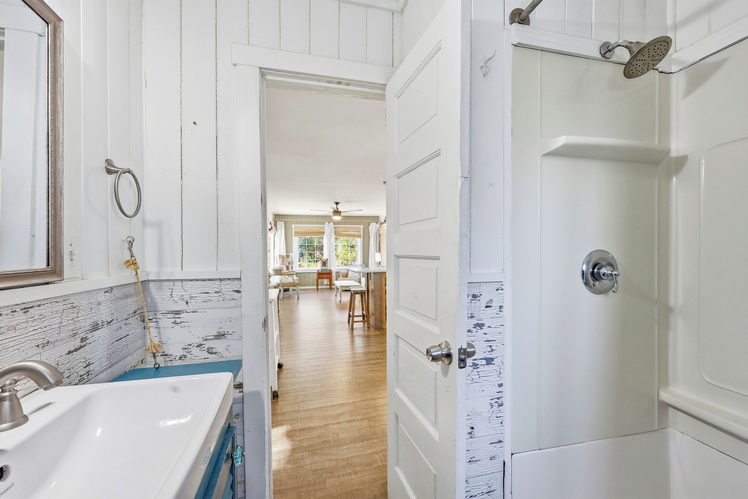 A bathroom with a sink, mirror, and shower.