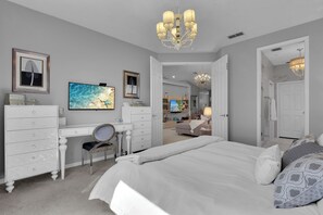 A bedroom with a bed, a desk, a chair, and a television.