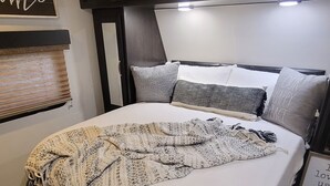 Une chambre à coucher comprenant un lit, une tête de lit, une table de chevet et une étagère fixée au mur.