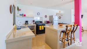 A modern kitchen with a central island, a stove, and a refrigerator. - Casa Perla Suite 1 a 2 Bdrm Caribbean Oceanfront Condo w/ dipping pool (Isla Mujeres)