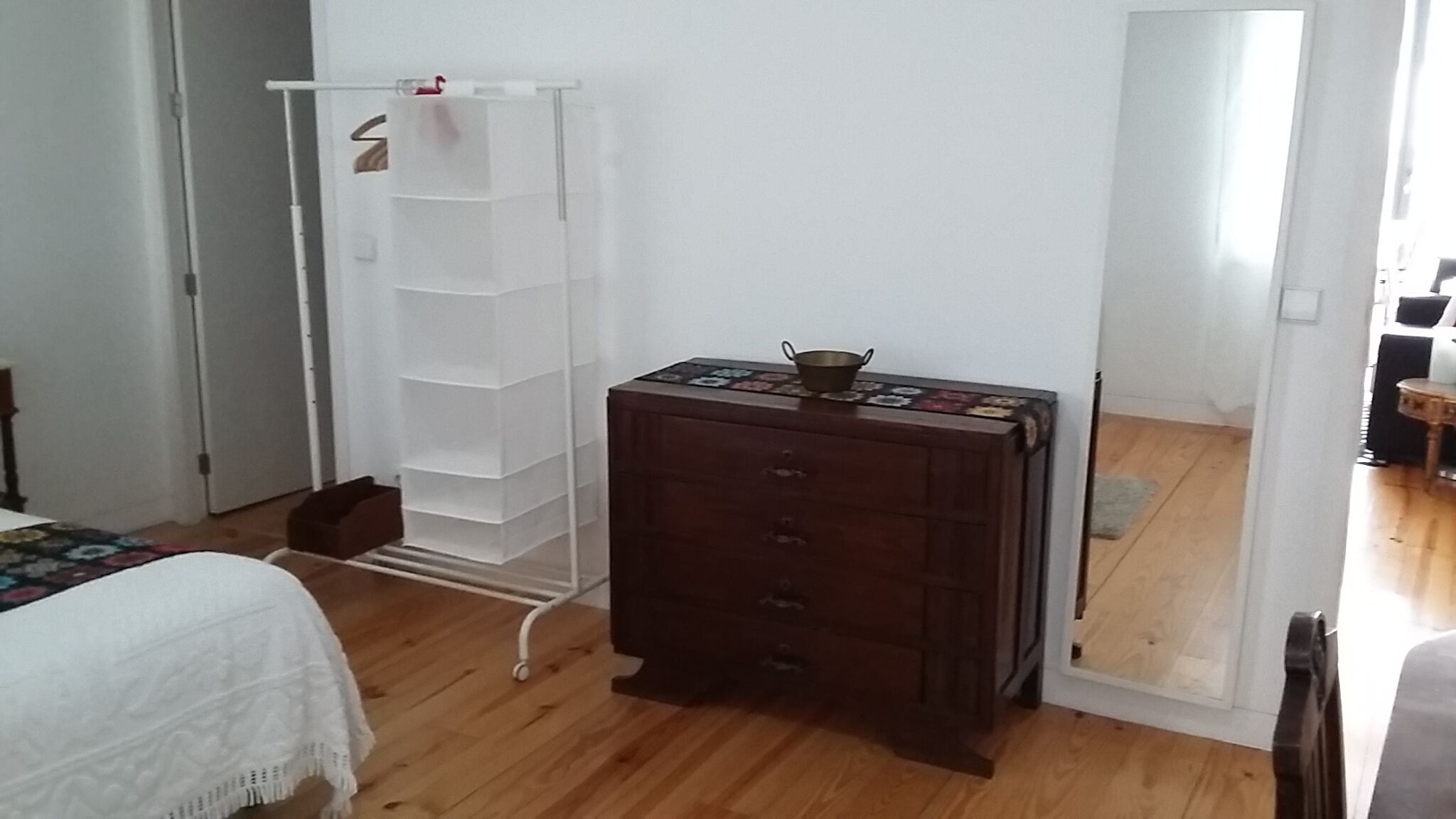 Un dormitorio con un aparador de madera, un armario blanco y una cama con cubrecama blanco.