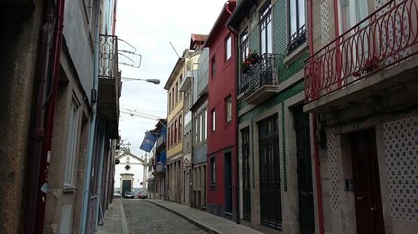 A narrow street lined with multi-story buildings, some with balconies and decorative railings. - Casa 45 (Porto)