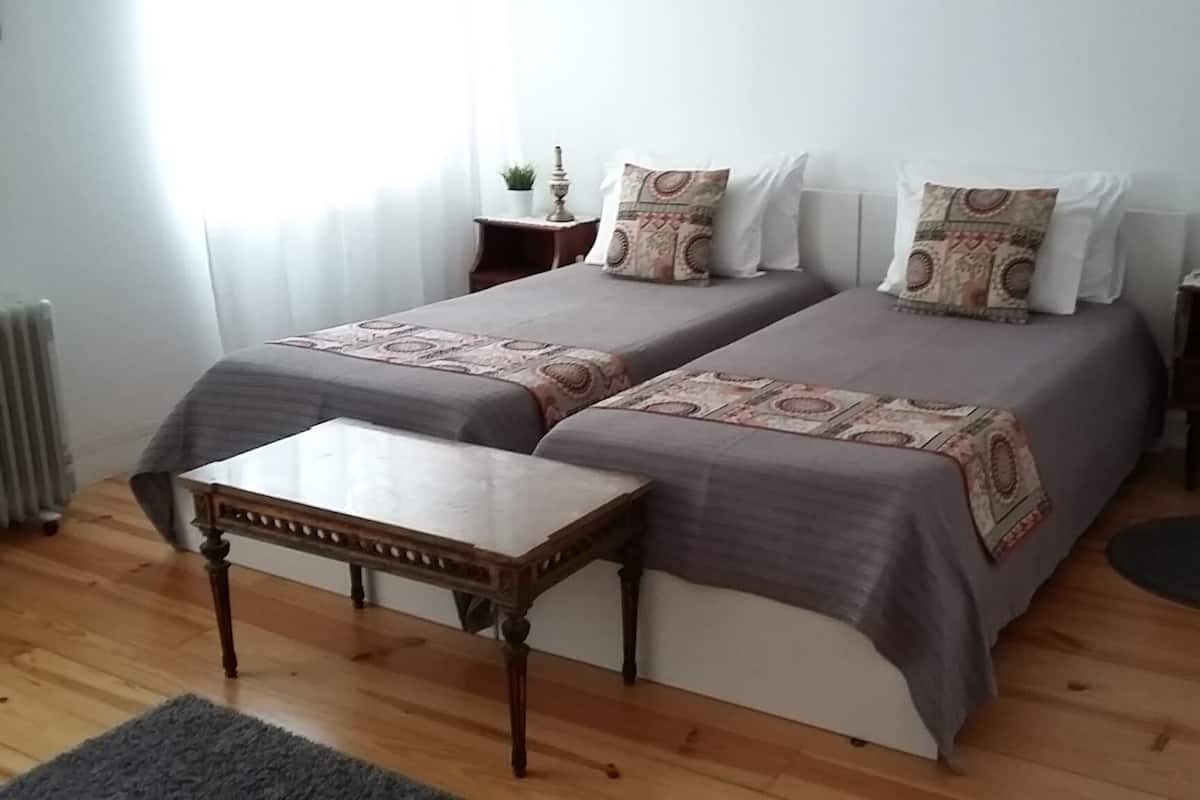 En dubbelsäng med ett mönstrat överkast, ett sängbord, en liten matta och ett element.