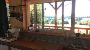Eine Küche mit Blick auf die Landschaft, einem Wasserkocher, einer Kaffeekanne und einem Spülbecken.
