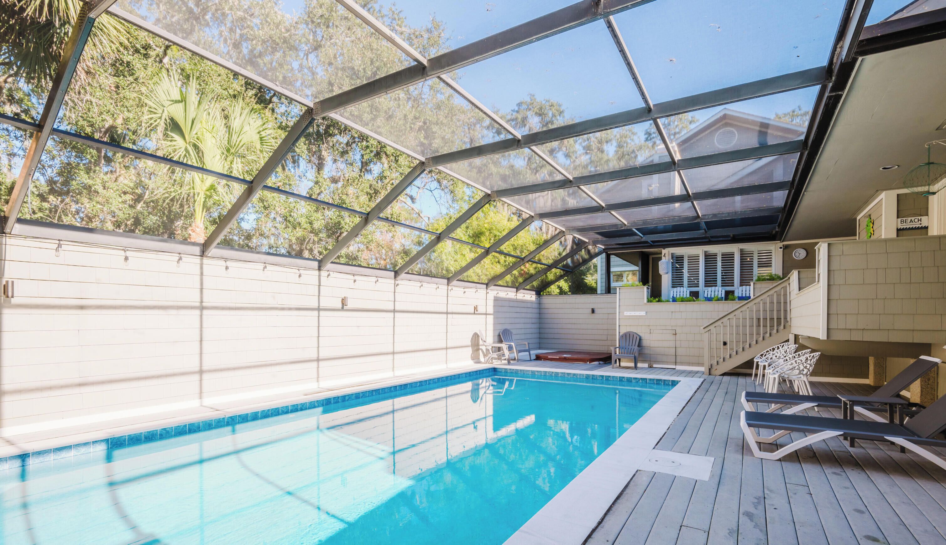 Una piscina techada con vistas a una casa y árboles.