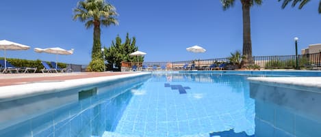 Una piscina al aire libre de temporada, sombrillas, tumbonas