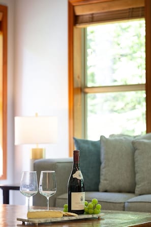 A table with a bottle of wine, two glasses, a piece of cheese, and grapes. - Upgraded Mountainside 3BR TH Ski-in, w/Private HT (Whistler)