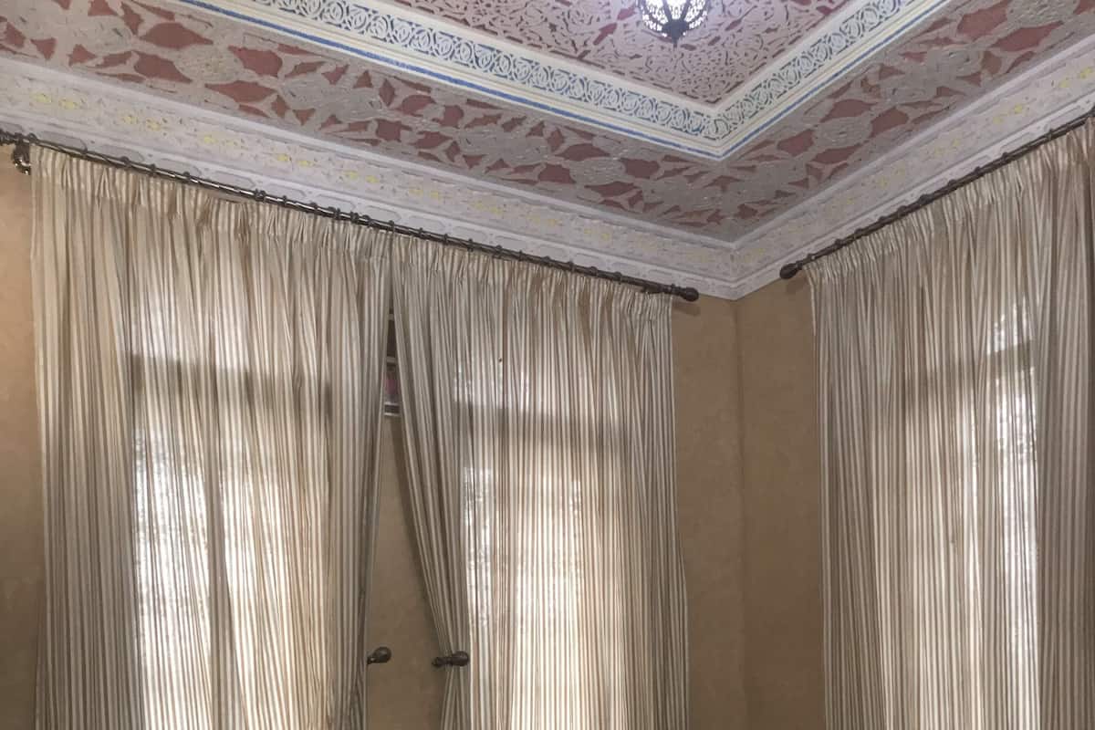 A bedroom with a bed, curtains, and a decorative ceiling.