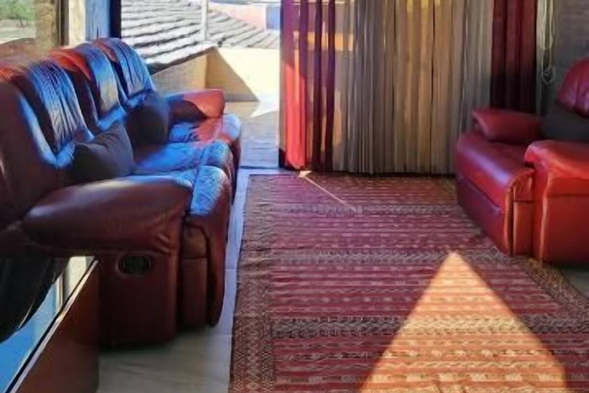 A spacious living area with a large window, a red sofa, a blue sofa, and a red armchair.