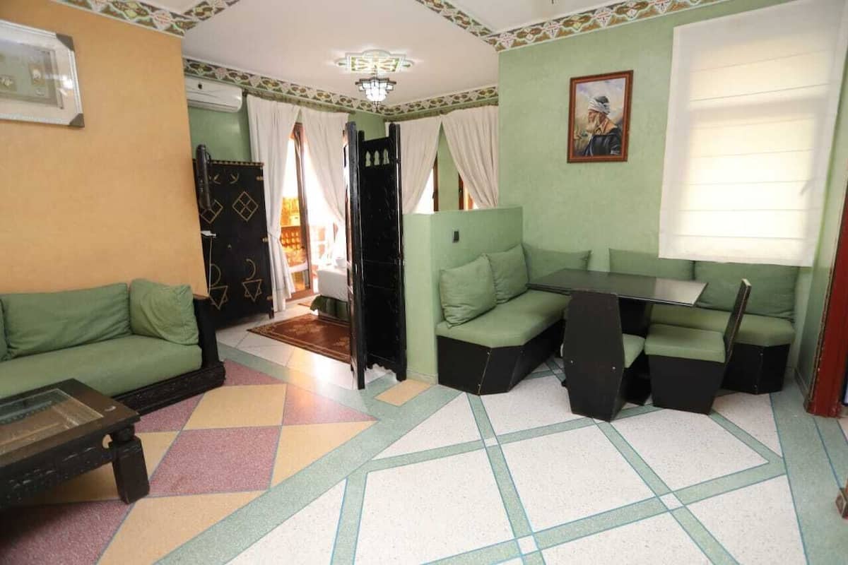 A living room with a sofa, a small table, and a green couch.