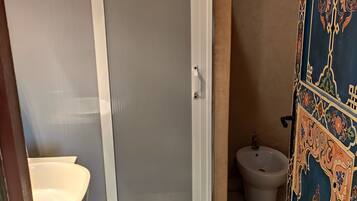 A bathroom with a toilet, bidet, and a shower with a glass door.