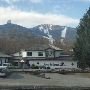 Een gebouw met de tekst 'Alpine Ski Center' en een piste op de achtergrond.