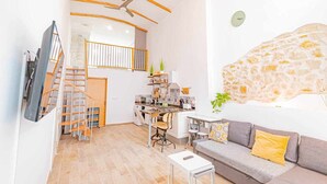 A modern living room with a grey sofa, a small table, and a staircase leading to an upper level. - SunCastle Romantic Loft (Alicante/Alacant)