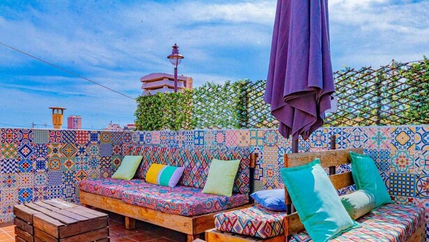 A rooftop terrace with colorful tiled walls, wooden furniture, and a purple umbrella. - SunCastle Romantic Loft (Alicante/Alacant)