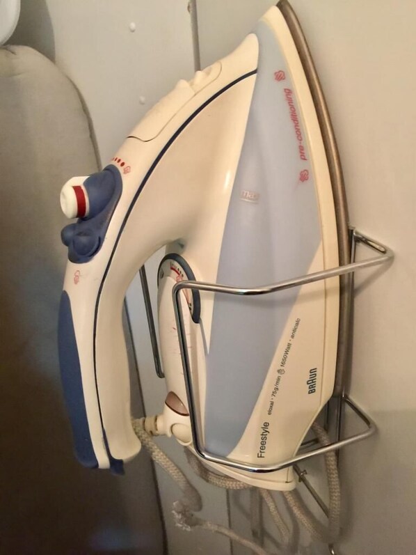 A Braun Freestyle 1050W portable iron with a steam function, mounted on a wall.