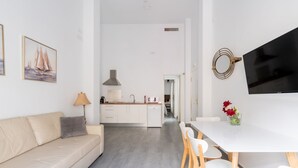 A modern, well-lit living room with a sofa, a dining table with chairs, a kitchen area, and a TV mounted on the wall. - Sanlúcar de Barrameda  6 (Sanlucar de Barrameda)