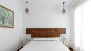 A bedroom with a large bed, wooden headboard, two bedside tables with lamps, and a framed picture on the wall.