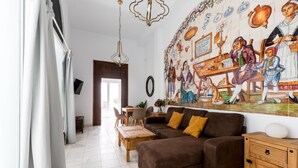 A living room with a brown sofa, wooden side table, and a mural on the wall.