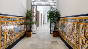 A hallway with ornate tiled walls, a metal gate, and potted plants.
