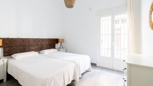 Un dormitorio con dos camas, cabecero de madera, lámpara de noche y ventana con vistas.