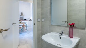 A modern bathroom with a sink, mirror, and a door leading to a dining area. - Sanlúcar de Barrameda  3 (Sanlucar de Barrameda)
